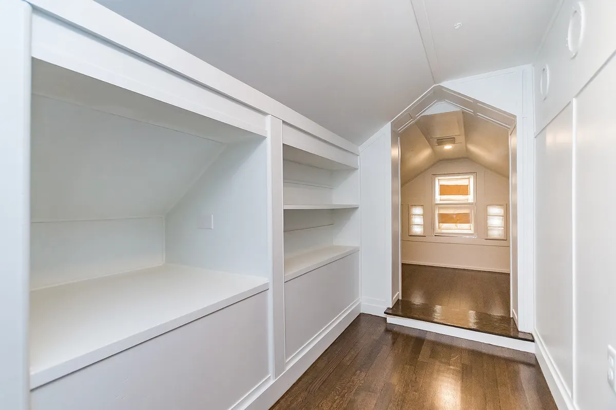 Renovated Newton attic on Ridge Avenue with built-in white shelving and a small dormer window nook