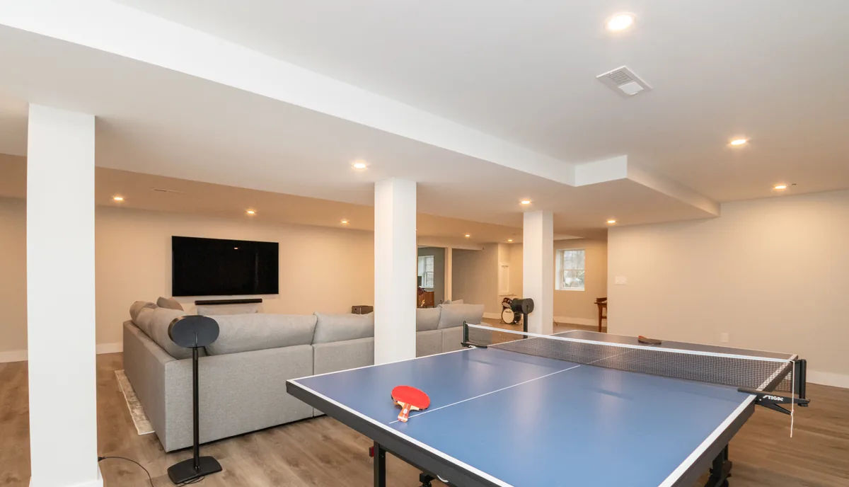 Finished Lexington basement on East Street with a gray sectional, mounted TV, and ping pong table