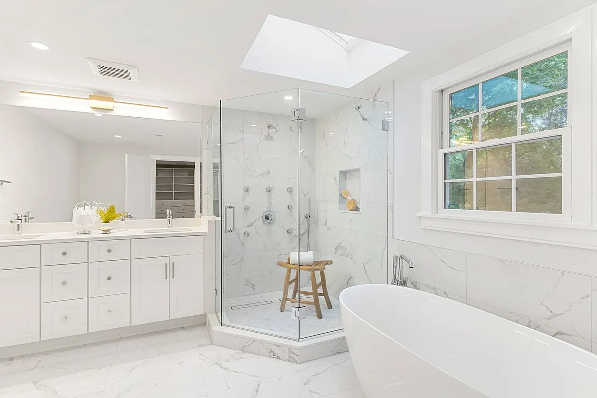 A completed Bay State bathroom in Greater Boston — marble shower surround, freestanding soaking tub, and skylight