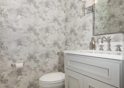 South Street Needham guest bathroom with a marble-look porcelain floor and brass fixtures