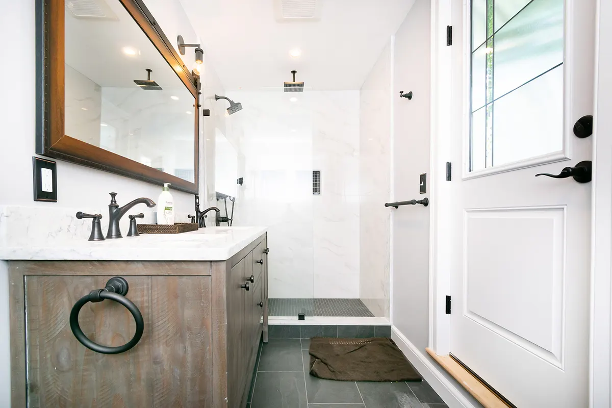Renovated Brookline bathroom on Welland Road with wood vanity, marble counter, bronze fixtures, and walk-in shower