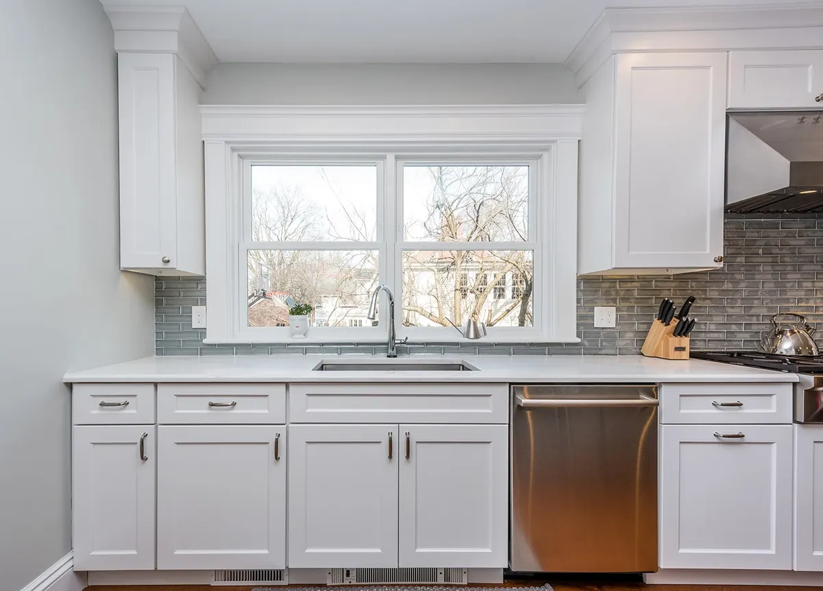 A white shaker kitchen with a gray glass backsplash: a Bay State Remodeling project in Newton