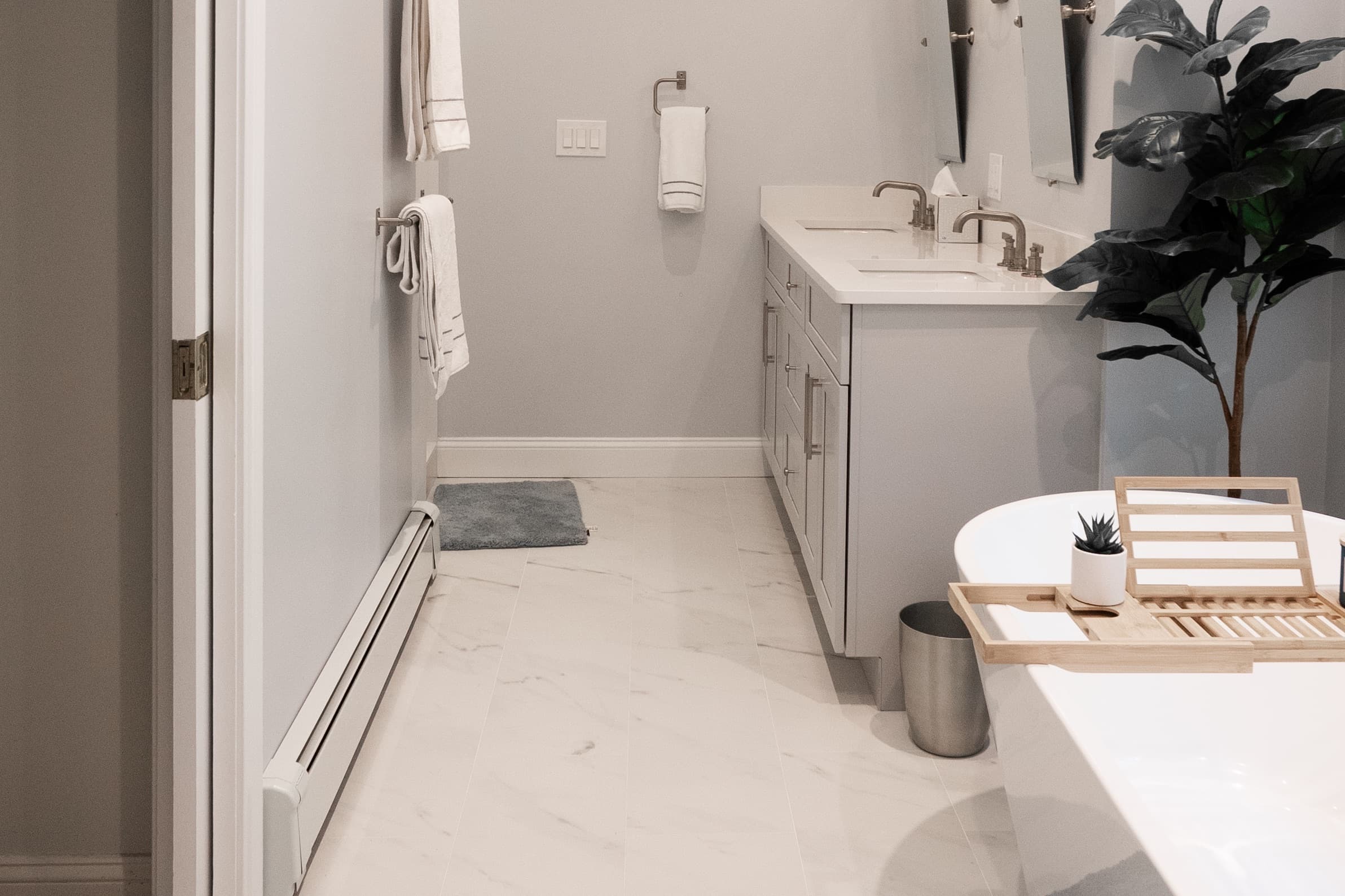 Renovated Brook Trail Rd Wayland bathroom with freestanding soaking tub, gray vanity, and marble-look tile flooring