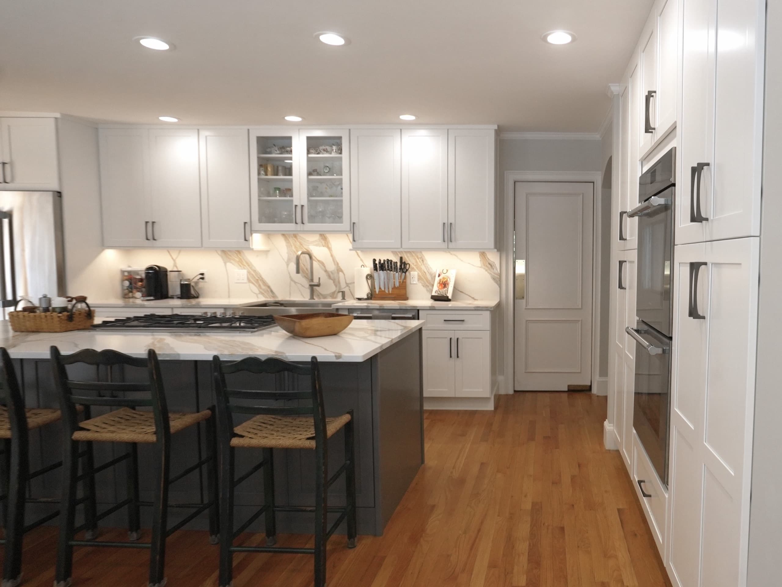Brook Trail Rd. Wayland kitchen with white shaker cabinets, dark island, and marbled quartz waterfall counters
