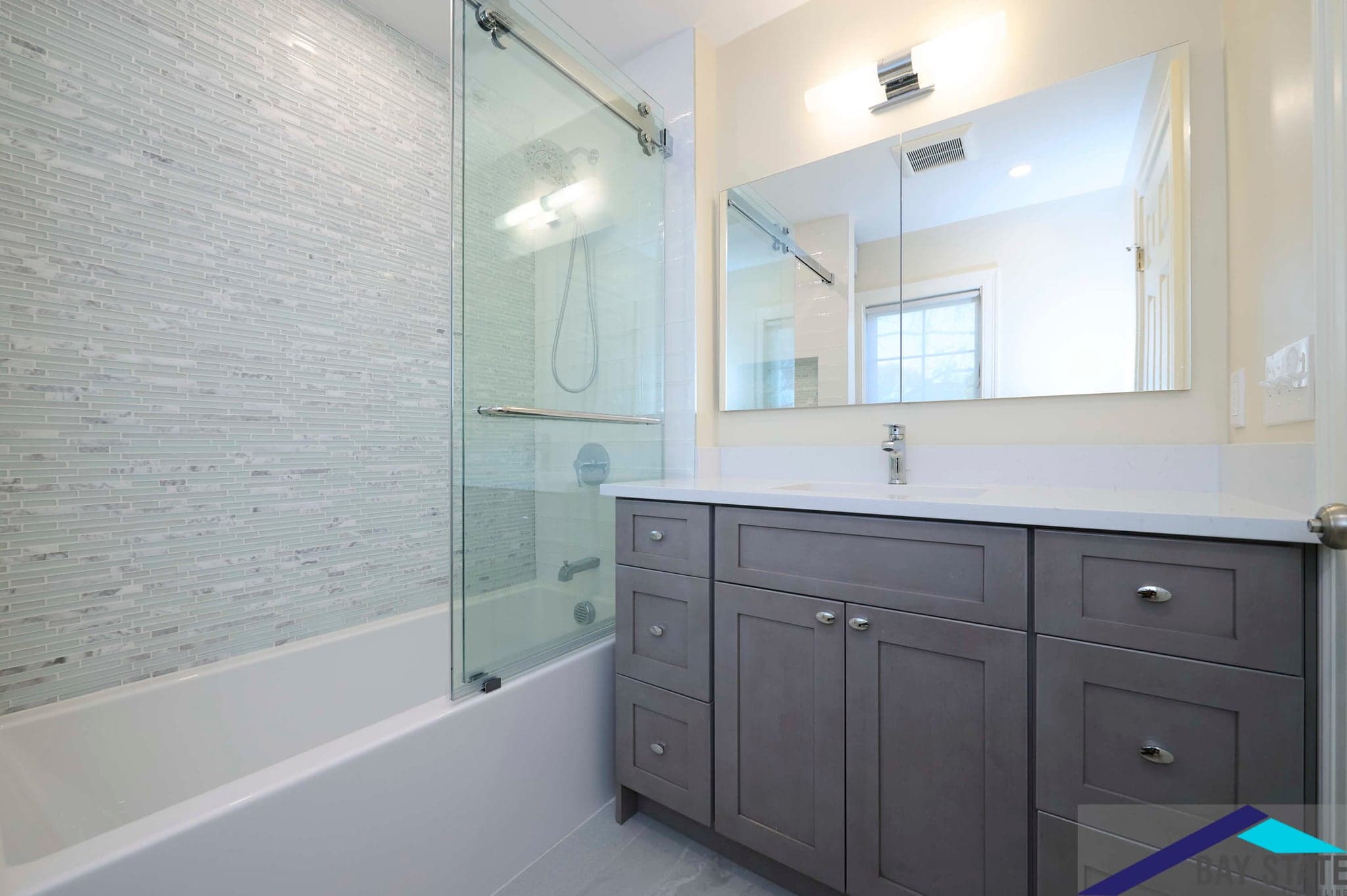 Renovated Chestnut St. Brookline bathroom with gray shaker vanity, white quartz counter, and mosaic tile shower