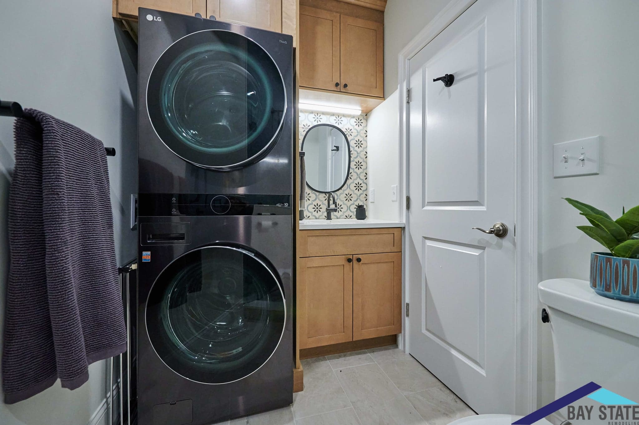 Lamartine St. Jamaica Plain laundry nook with a stacked black washer-dryer and patterned tile backsplash