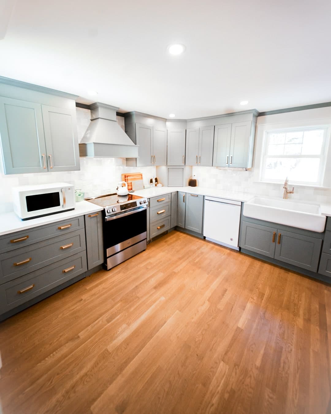 Richgrain Ave. Waltham kitchen with gray shaker cabinets, white quartz counters, a farmhouse sink and oak floors