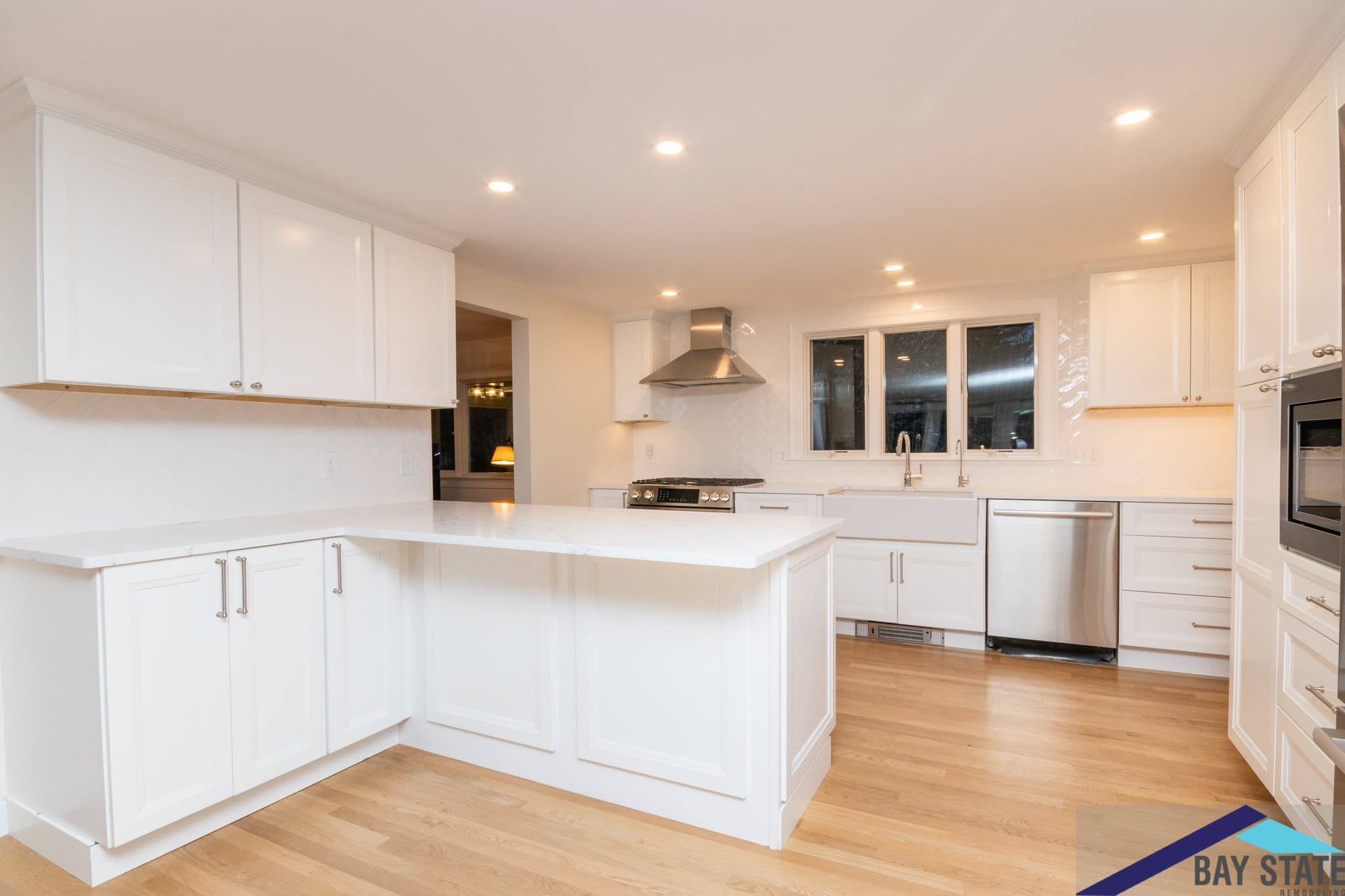 Sun Hill Ln. Newton kitchen with white cabinets, quartz waterfall island, and stainless range hood