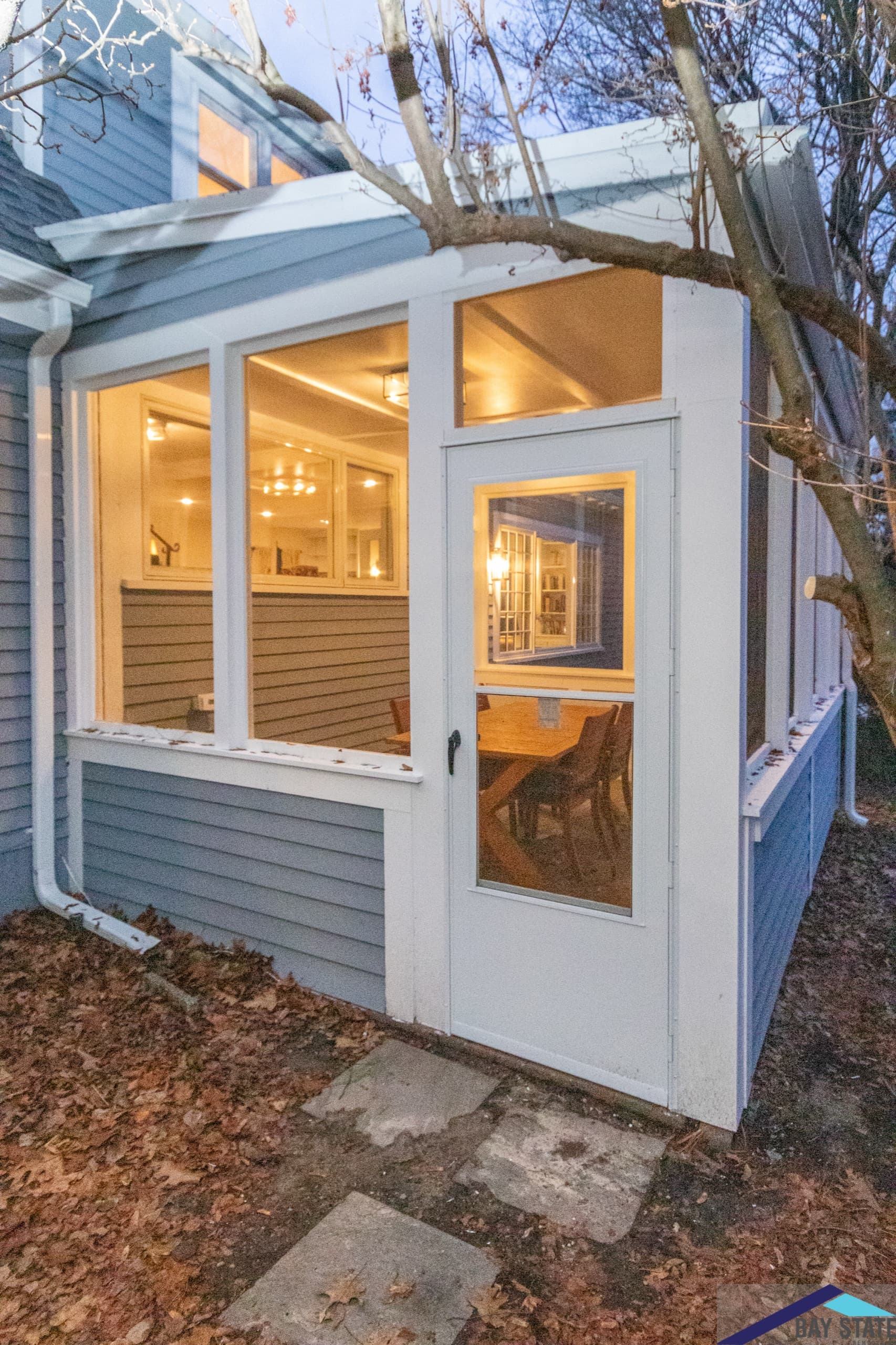 Sun Hill Ln. Newton three-season porch addition with blue-gray siding, white trim, and a glass door