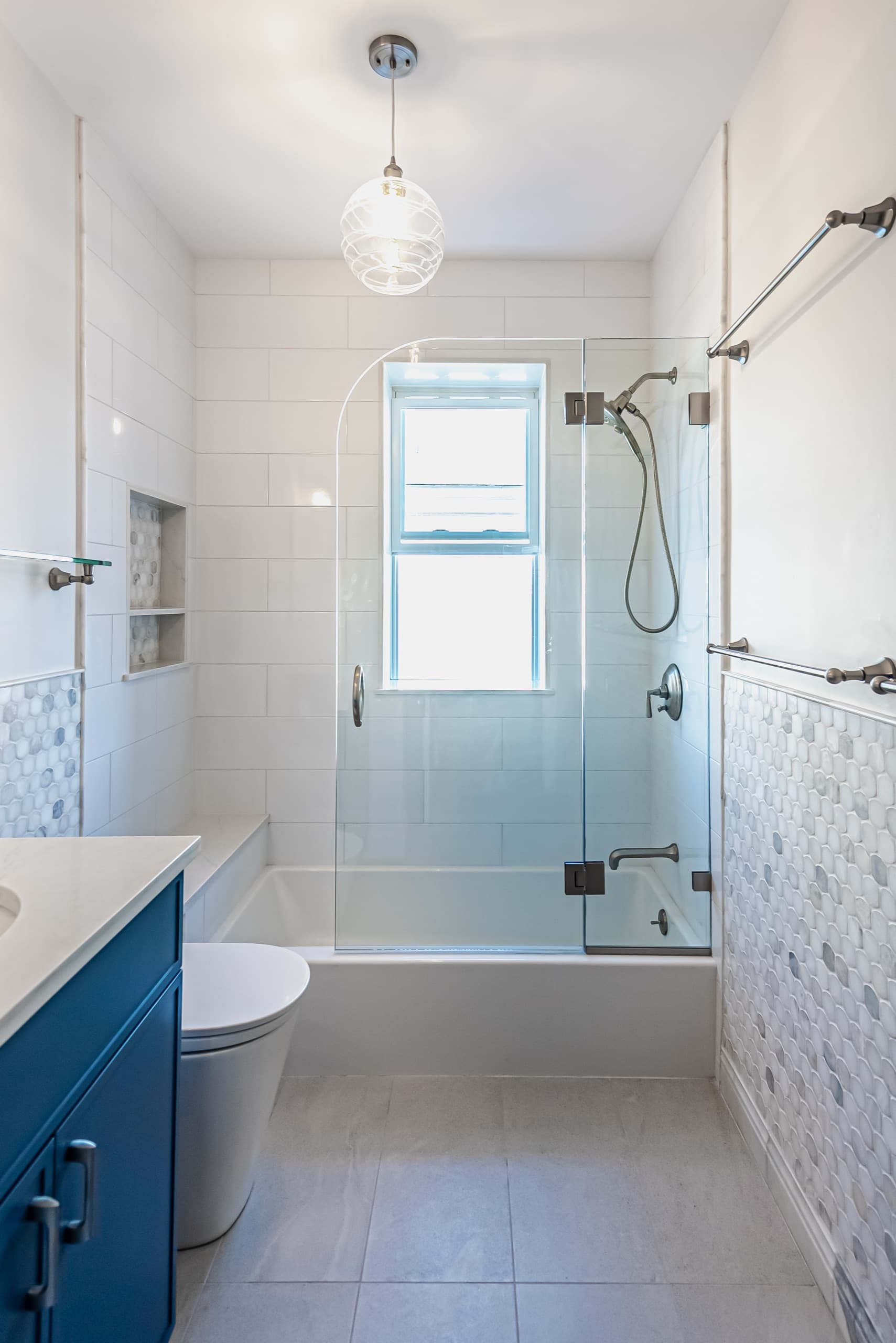 Renovated Tappan St. Brookline bathroom with white subway tile, frameless glass shower, and navy vanity