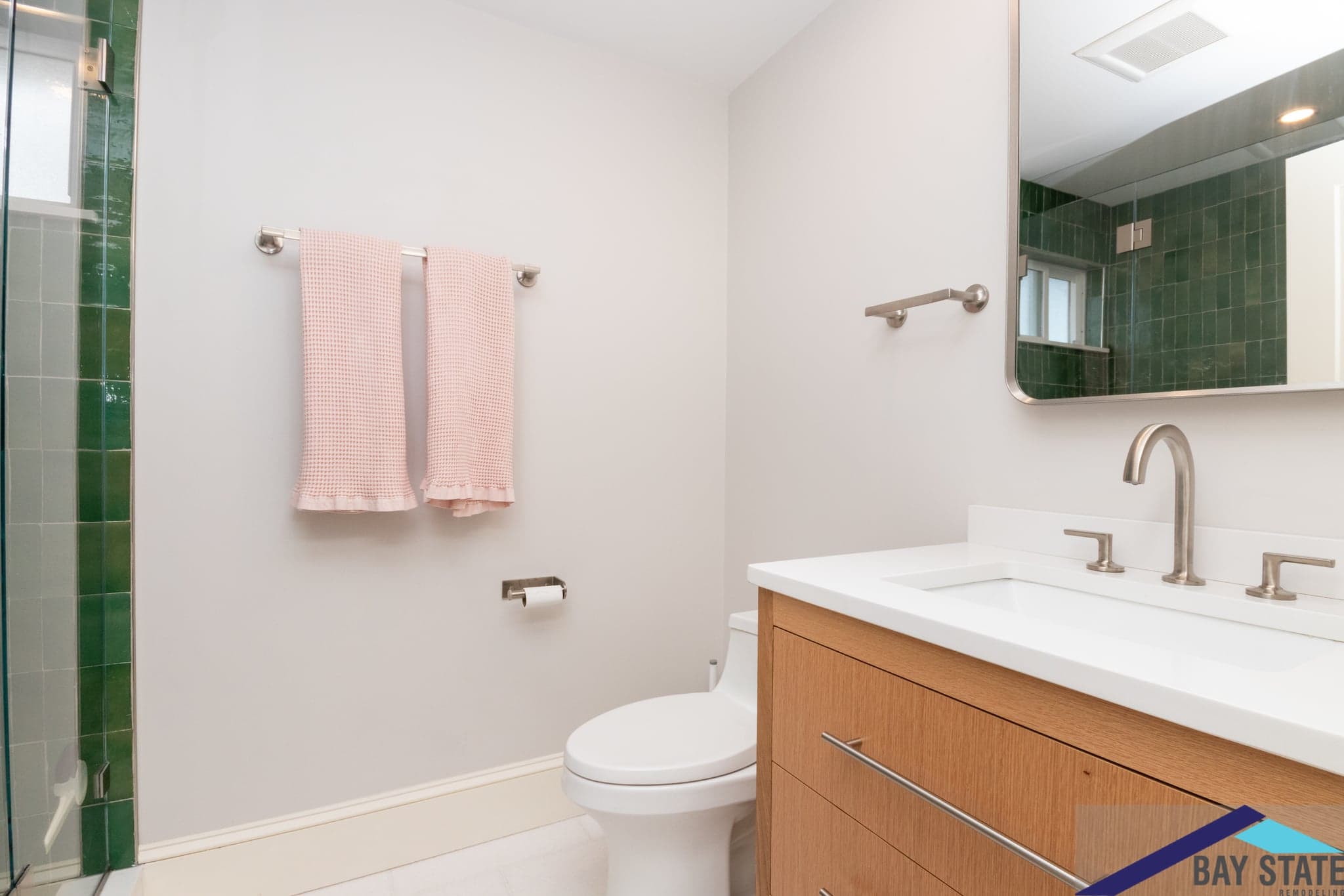 Renovated Trowbridge Ave. Newton bathroom with wood vanity, quartz counter, chrome fixtures, and pink hand towels