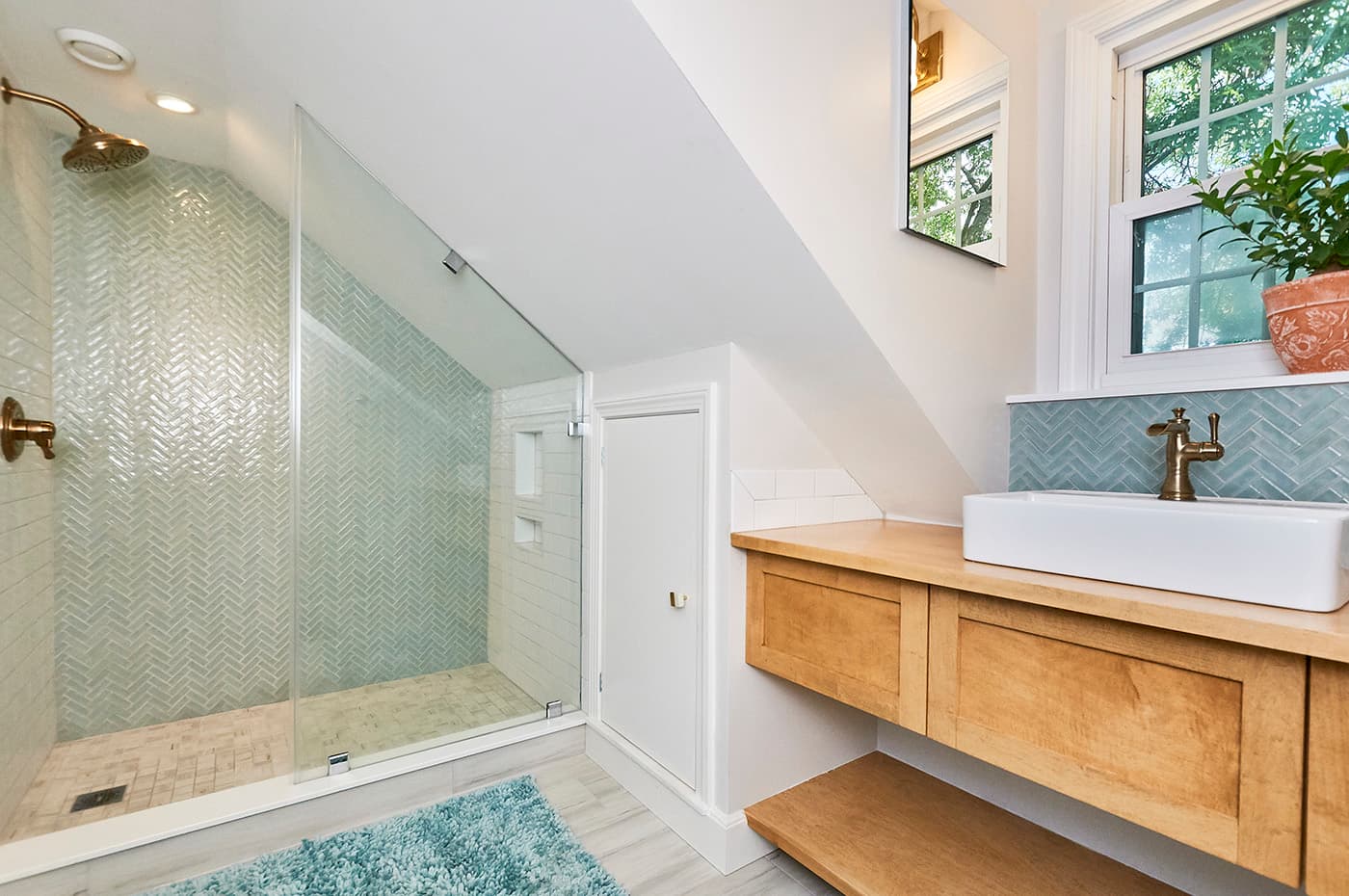 Renovated Third St. Cambridge bathroom with herringbone tile shower, brass fixtures, and a vessel sink vanity