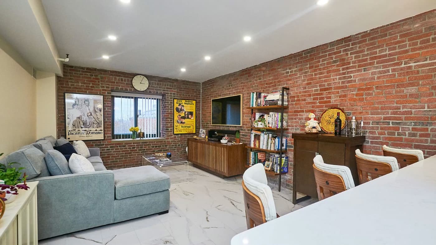 8th St. Charlestown whole-home remodel with an exposed brick living room, gray sectional and marble-look flooring