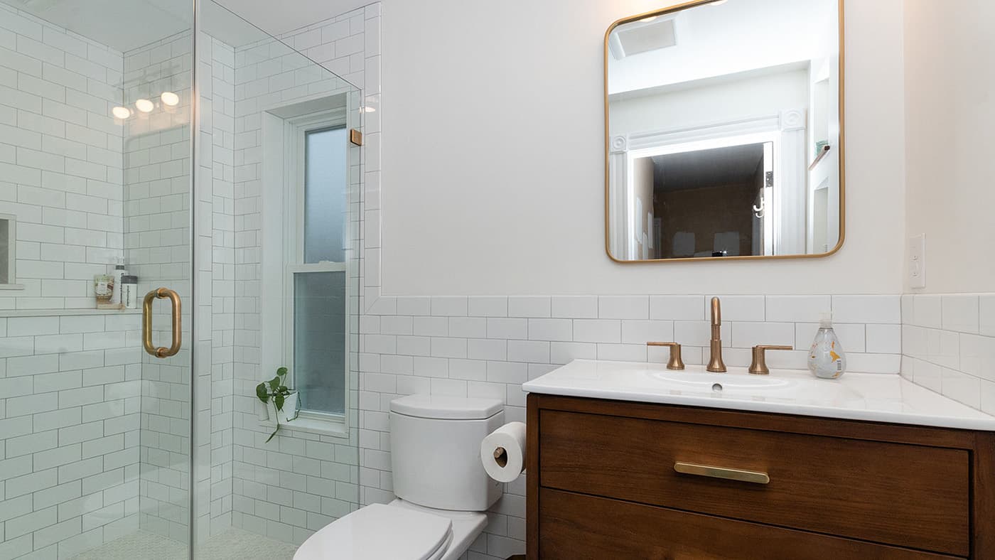 Renovated Adams St. Boston bathroom with white subway tile shower, brass fixtures, and wood vanity