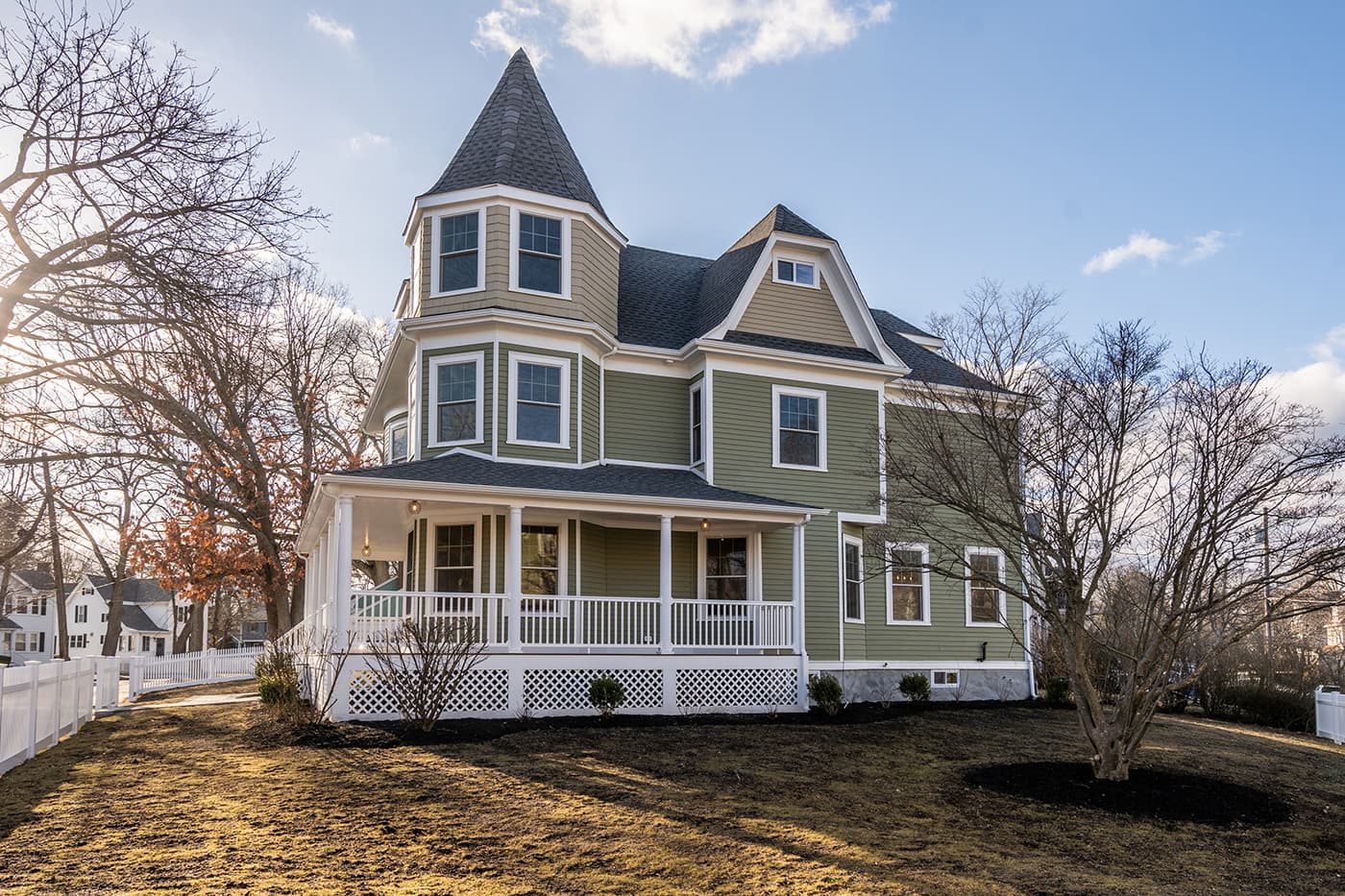 Auburndale Ave. exterior after whole-home renovation in Newton, with white picket fence and mature shade trees.