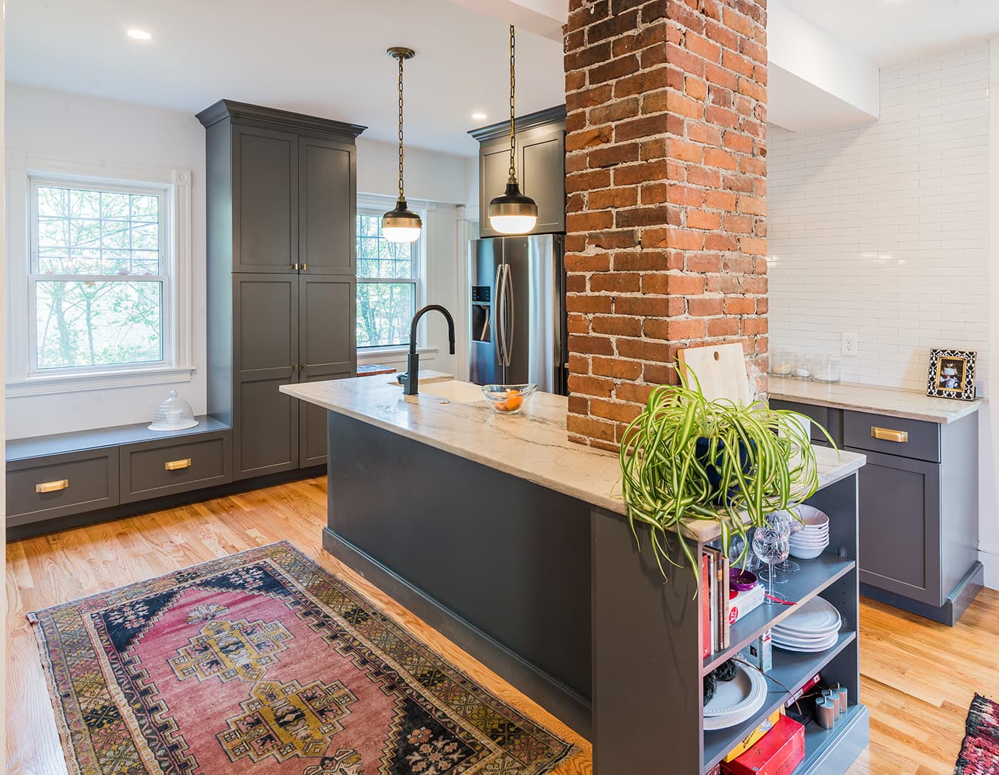 Bruce St. Dorchester kitchen with charcoal island, exposed brick column, and white subway-tile backsplash