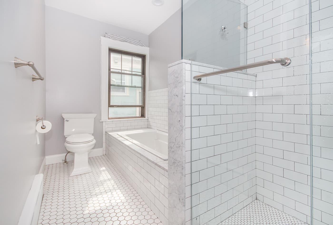 Renovated Bynner St. Jamaica Plain bathroom with white subway tile shower and marble tub surround