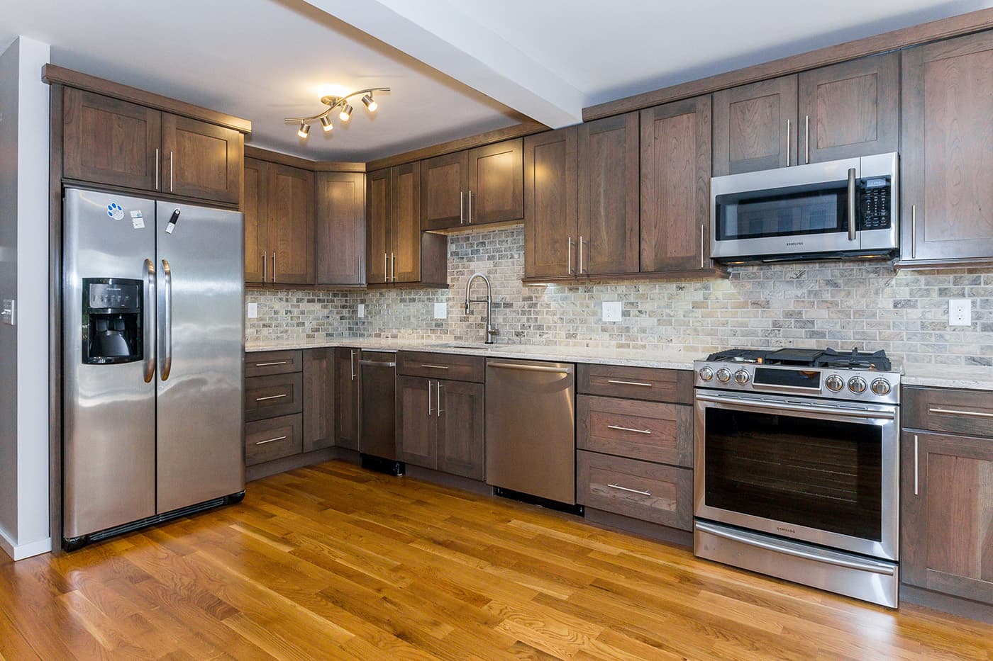 Captains Row Rear Chelsea kitchen with walnut shaker cabinets, stone-tile backsplash, and stainless appliances