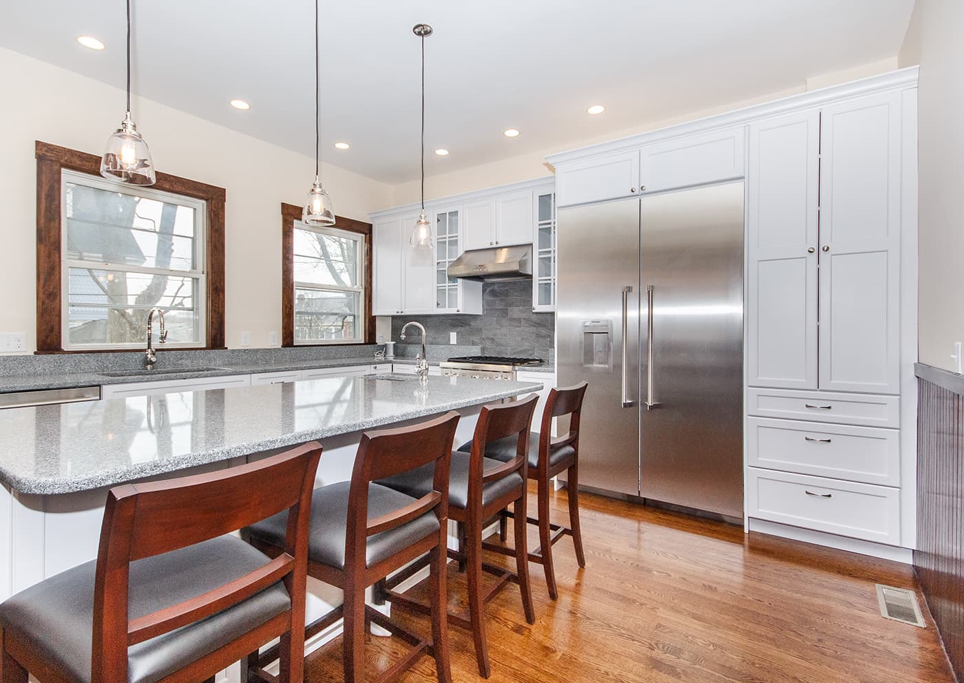 Carruth St. Dorchester kitchen with white cabinets, speckled granite counters, and dark wood-trim windows