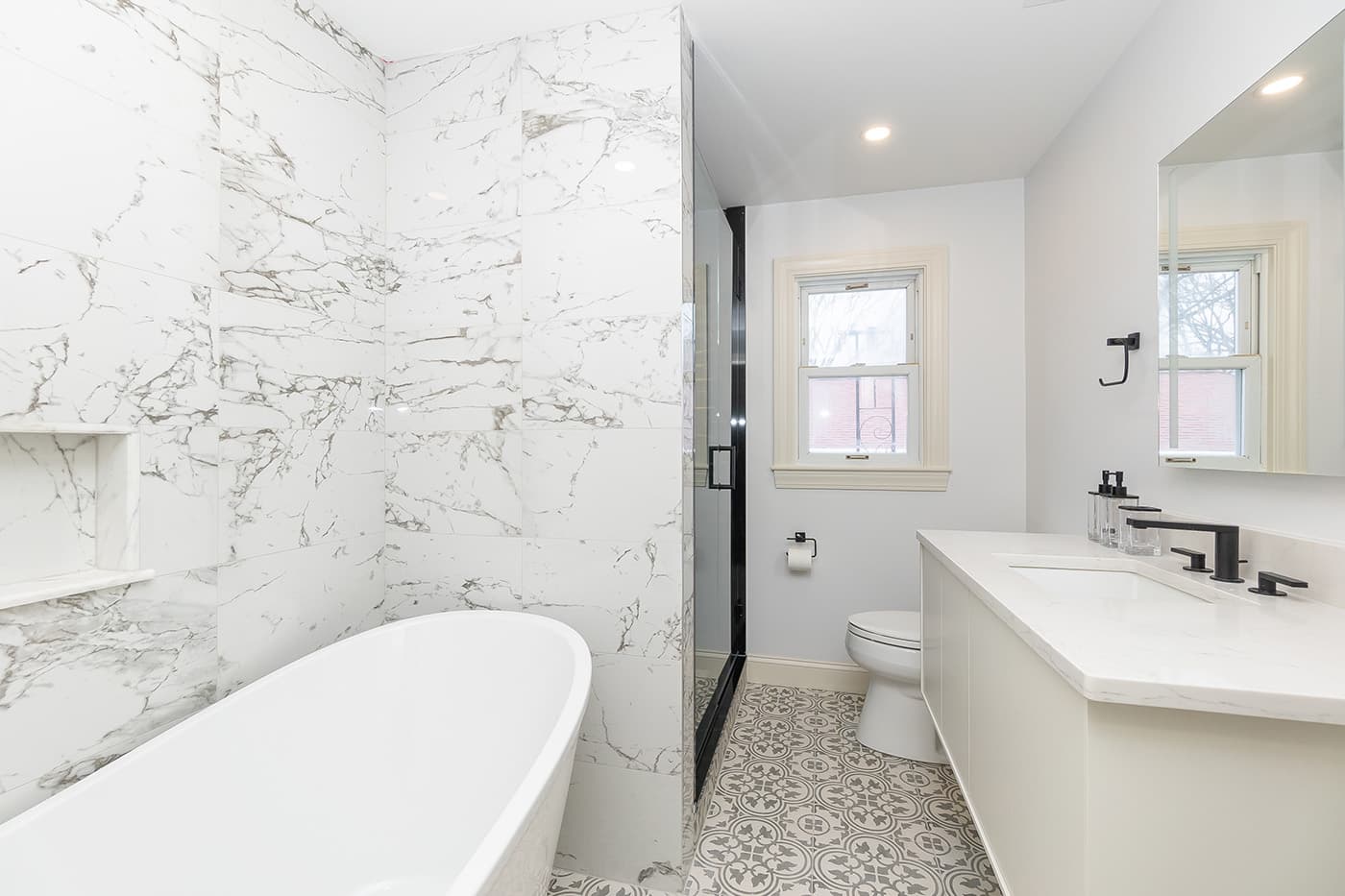 Renovated Cedrus Ave. Roslindale bathroom with veined marble tile walls and a freestanding soaking tub