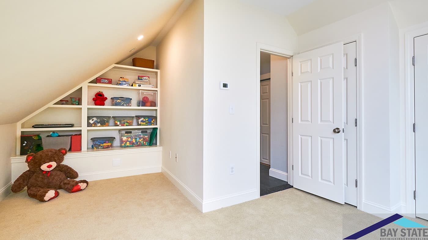 Cherry St. Newton attic remodel with sloped-ceiling built-in shelving, playroom storage, and plush carpet