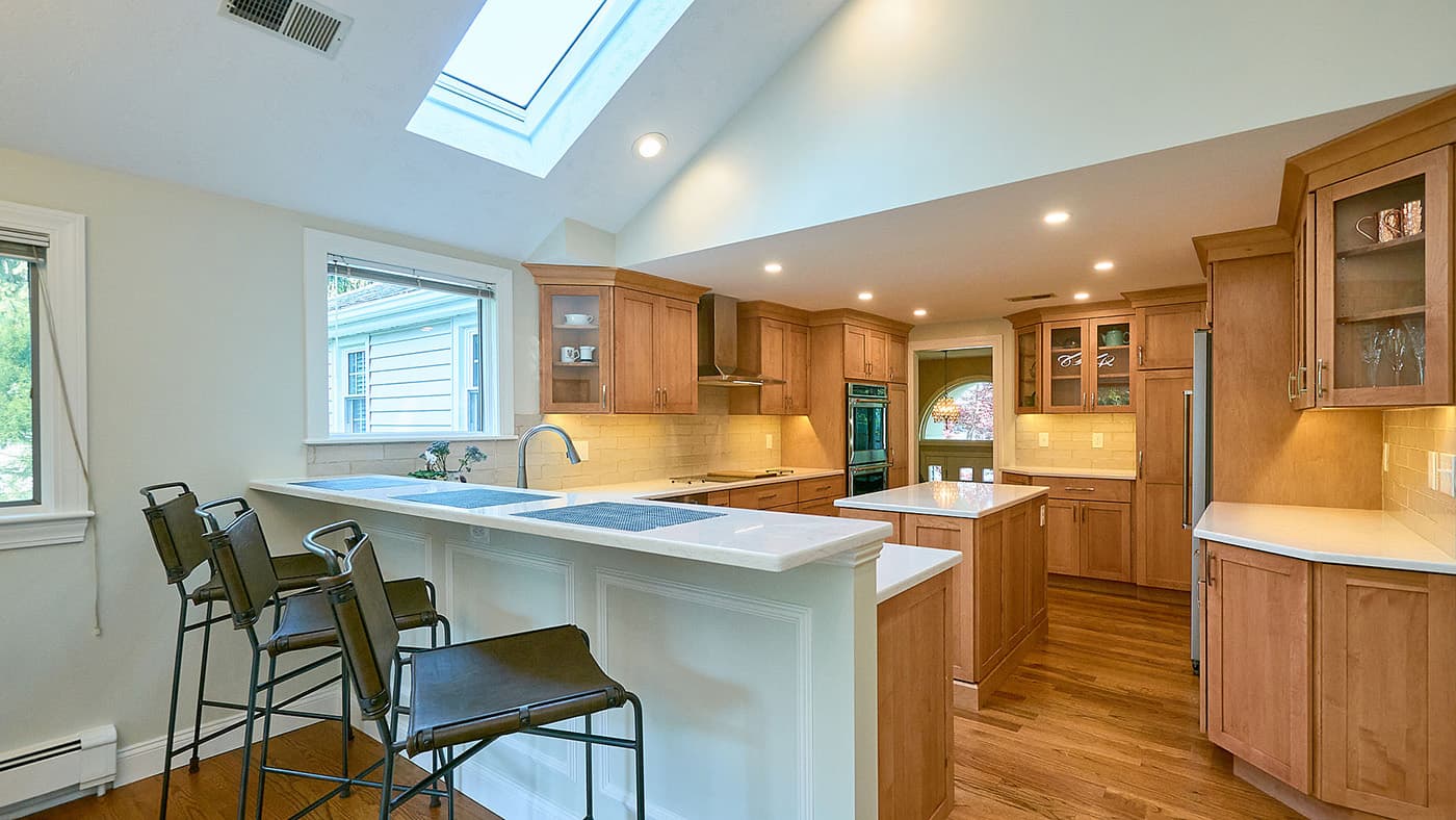 Cottonwood Rd. Wellesley kitchen with honey-oak cabinets, tile backsplash, and vaulted skylight ceiling