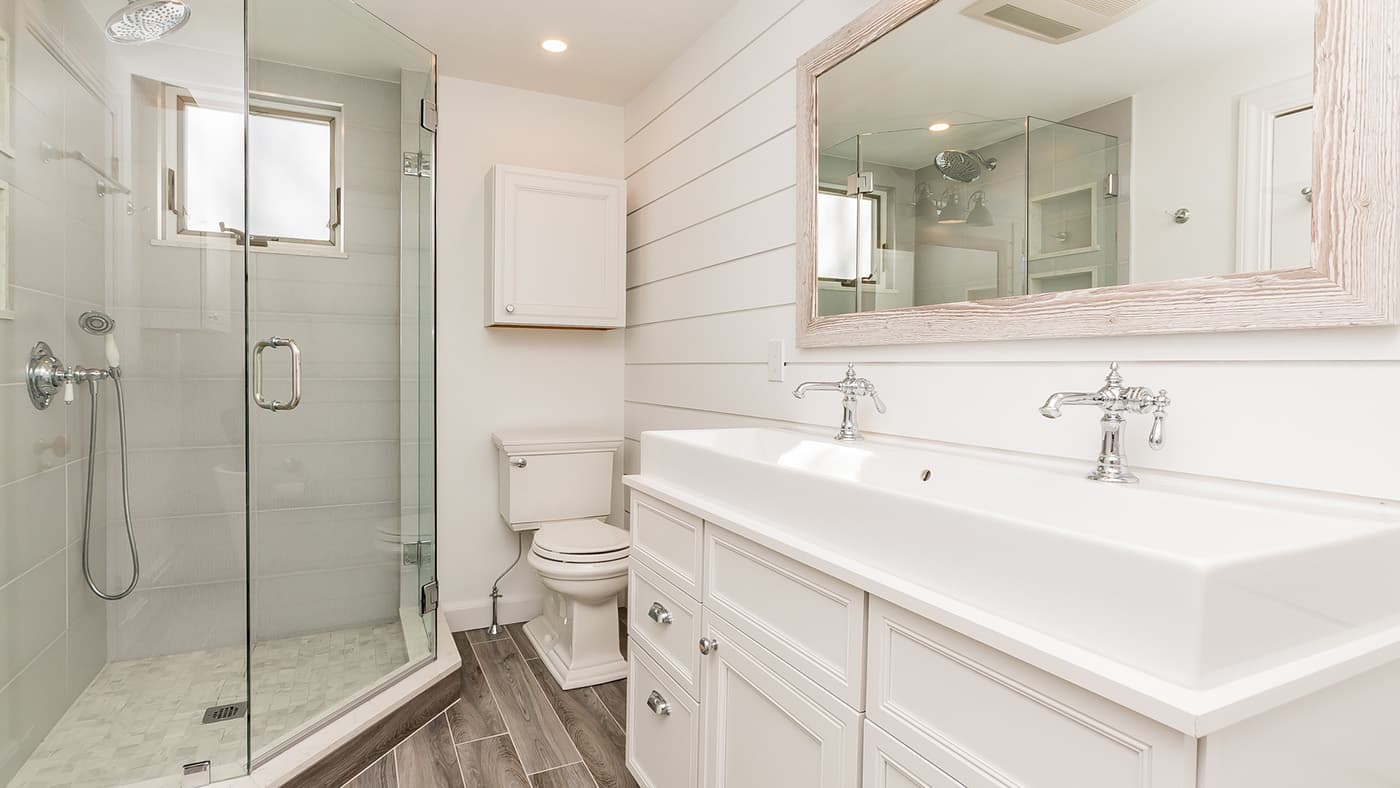Renovated Cross St. Belmont bathroom with shiplap walls, trough-style double vanity, and glass shower stall