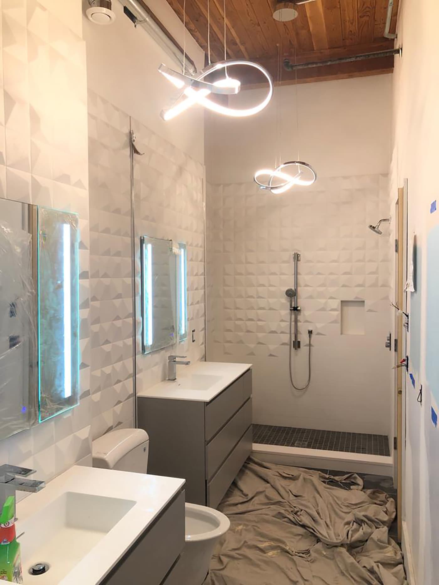 East 1st St. Boston bathroom mid-remodel with dimensional tile walls, wood ceiling, and pendant lighting installed