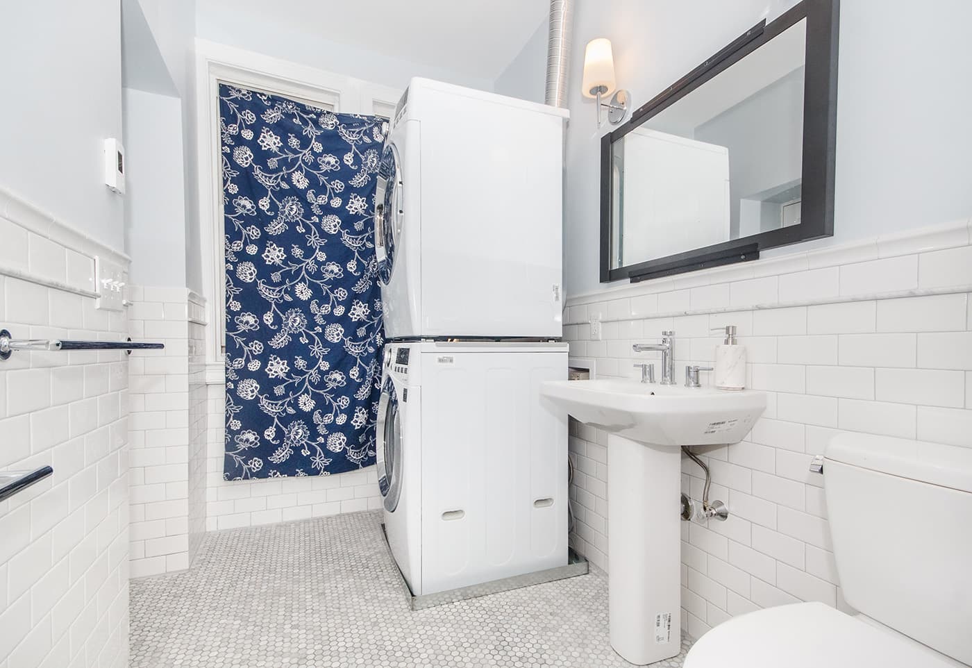 Renovated Euston St. Brookline bathroom with white subway tile, pedestal sink, and stacked laundry nook