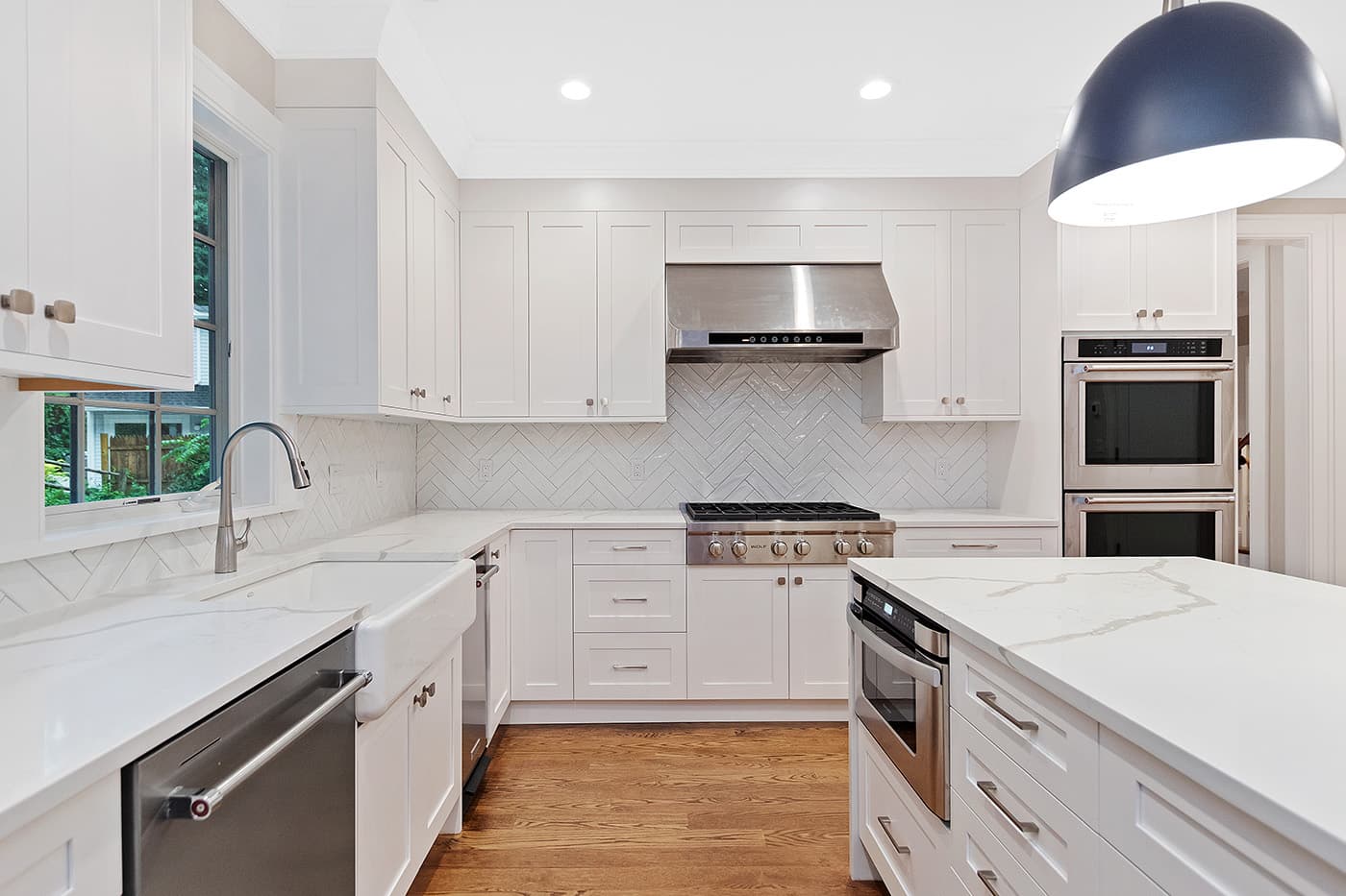 Garland Rd. Newton kitchen with white cabinets, herringbone-tile backsplash, and waterfall quartz island