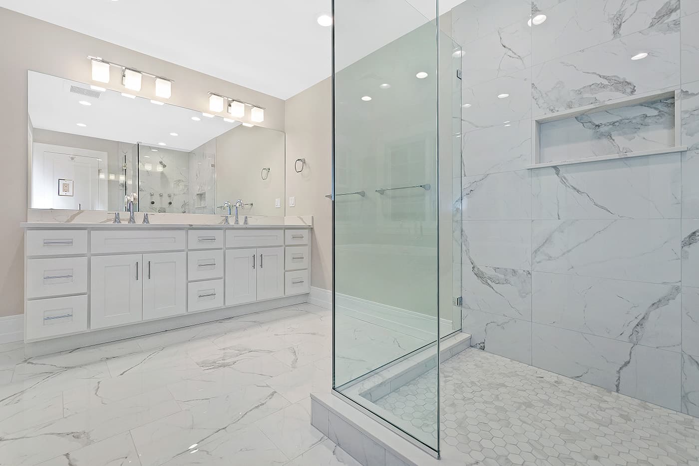 Renovated Garland Rd. Newton primary bathroom, white double vanity, marble floors, and frameless glass shower