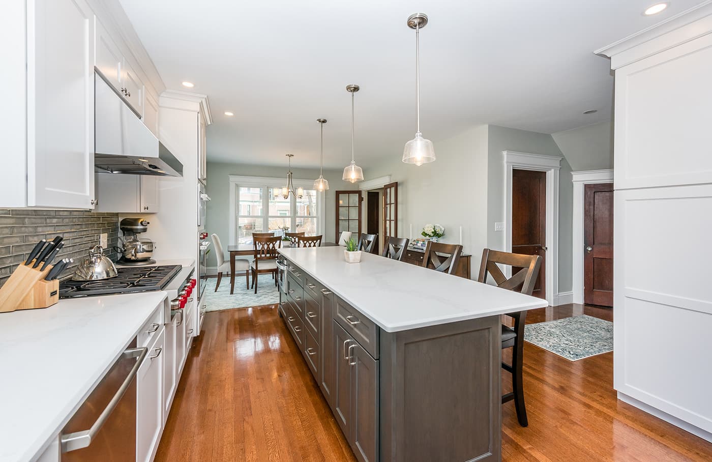 Grasmere St. Newton kitchen with white cabinets, charcoal-gray island, and glossy hardwood flooring