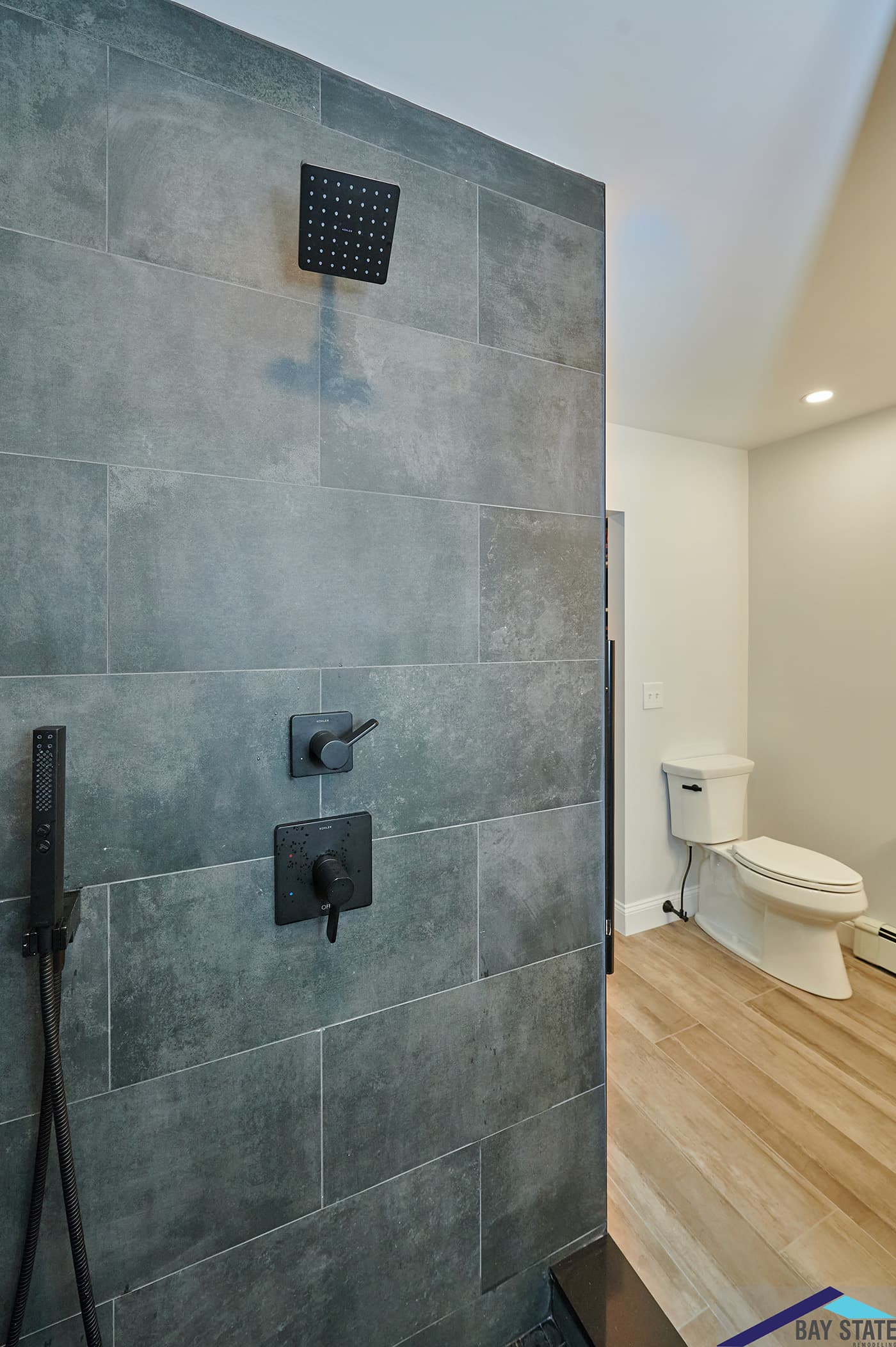 Hinckley St. Somerville slate-tile shower with black rain head opening toward the toilet area
