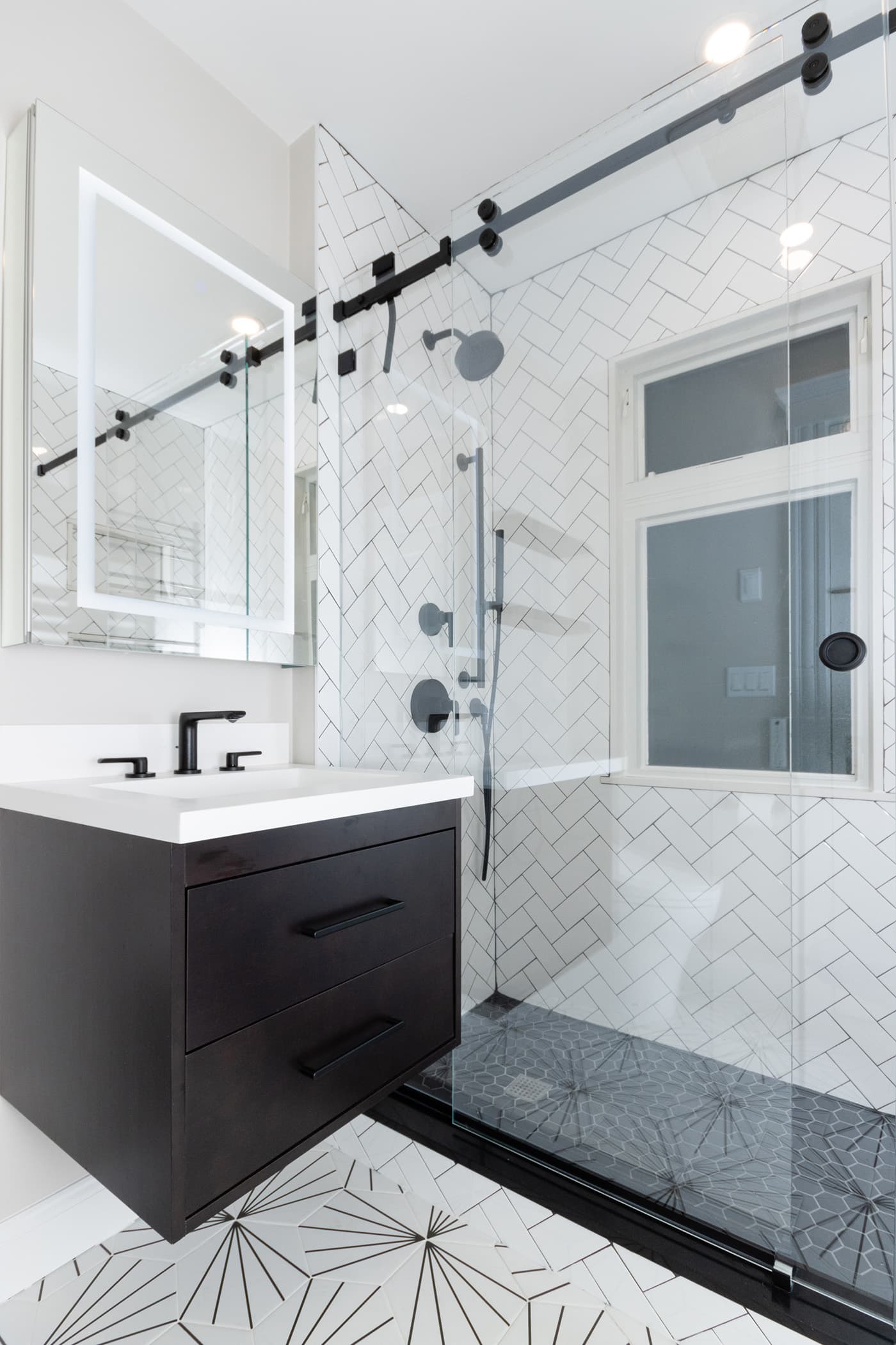 Hosmer St. Watertown bathroom herringbone shower beside a black vanity and starburst tile floor
