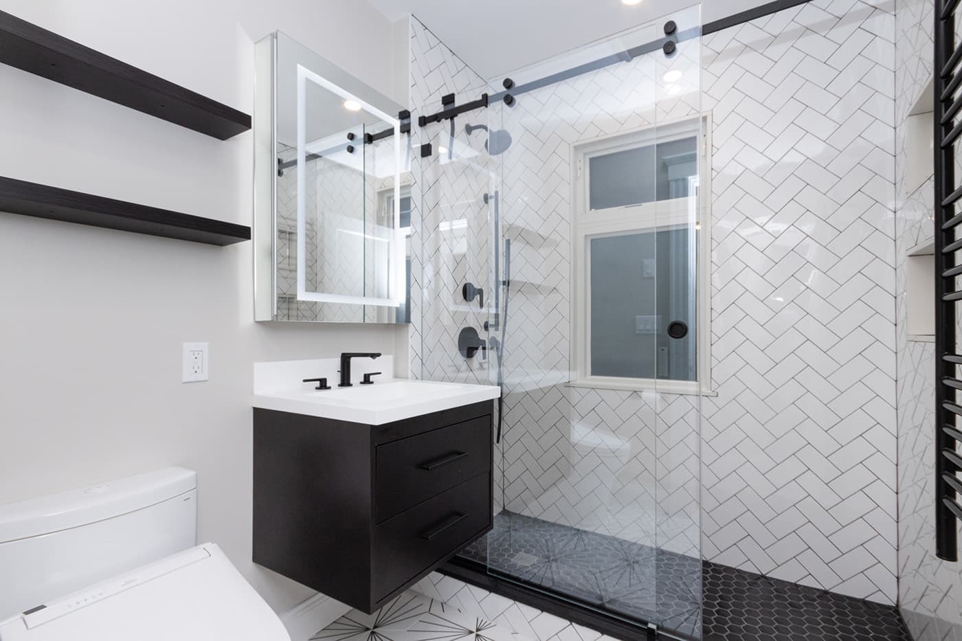 Renovated Hosmer St. Watertown bathroom with herringbone tile shower, black floating vanity, and black fixtures
