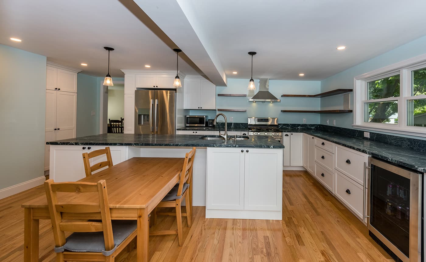 Joyce Rd. Arlington kitchen with white cabinets, dark soapstone counters, and floating wood shelves