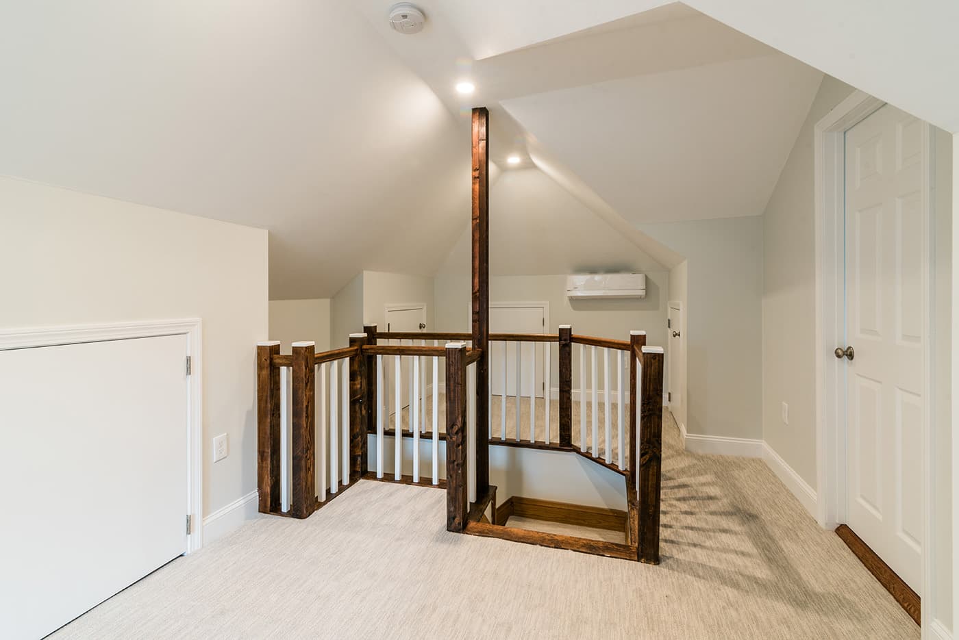 Madison St. Belmont attic remodel with vaulted ceiling, dark wood stair railing, and carpeted landing