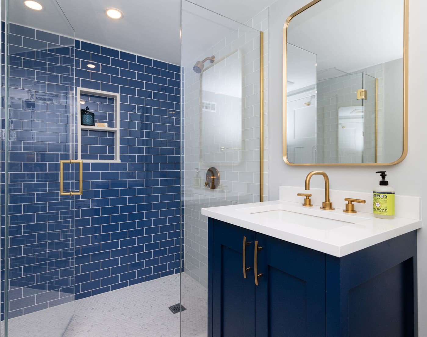 Renovated Maple Place, Jamaica Plain bathroom with navy subway tile shower, gold fixtures, and blue vanity