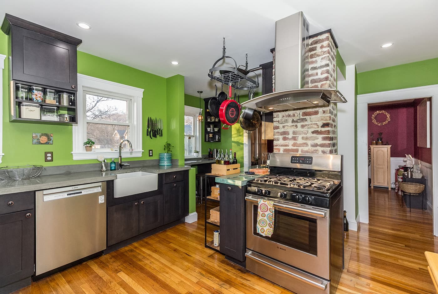 Minot St. Boston kitchen with dark cabinets, green walls, concrete-look counters, and exposed brick chimney
