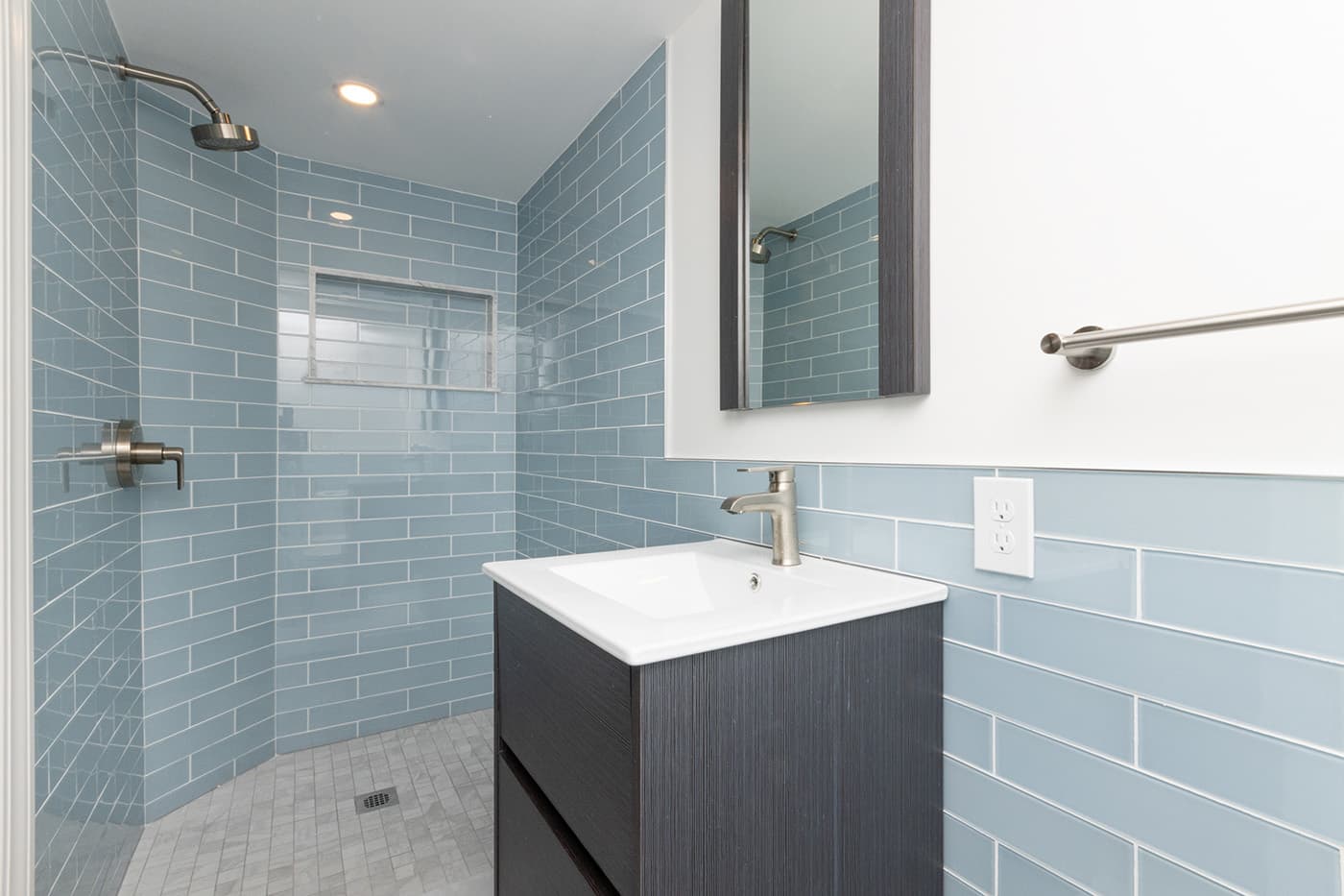 Renovated Mondamin Court Somerville bathroom with blue subway tile shower and black wood vanity