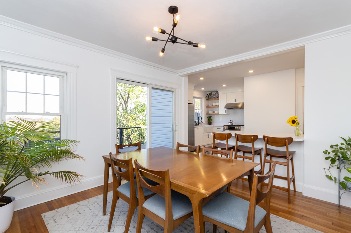 Renovated N Crescent Circuit Boston dining room with mid-century table, kitchen visible beyond
