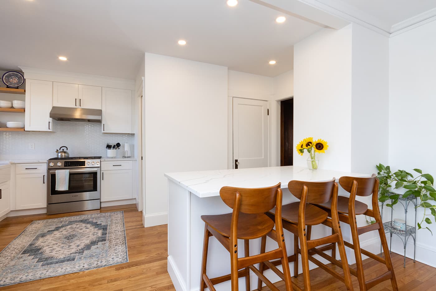 N Crescent Circuit Boston kitchen island with quartz counter, wood barstools, and white cabinetry beyond