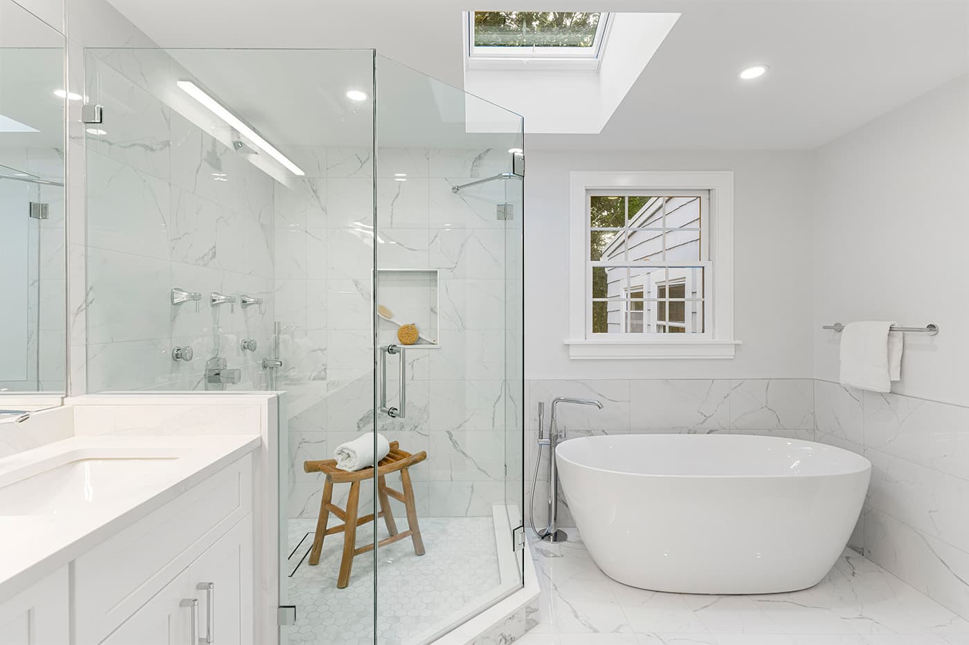 Renovated Potter St. Concord bathroom with a freestanding oval tub, marble tile walls, and a skylight