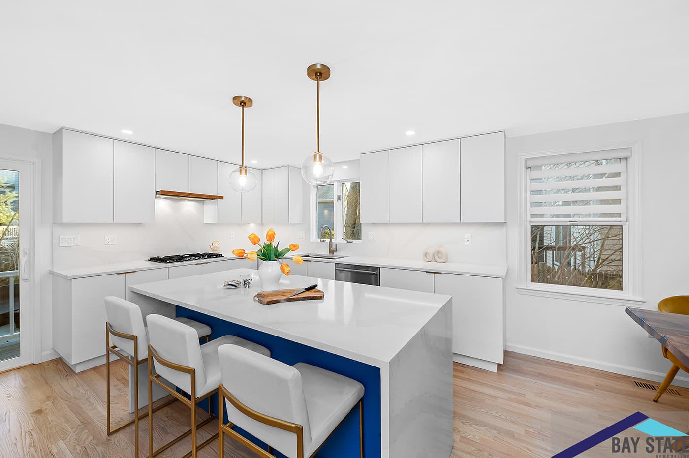 Prescott St. Arlington kitchen with white flat-panel cabinets, navy island base, and waterfall quartz counter