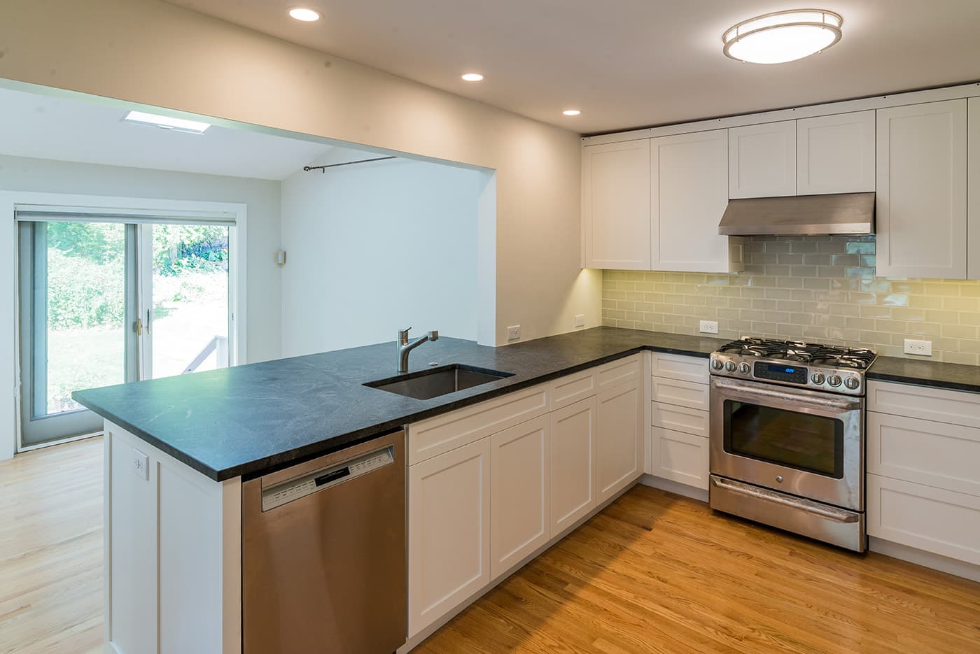Rolling Lane Newton kitchen with white cabinets, dark soapstone counters, and green subway-tile backsplash
