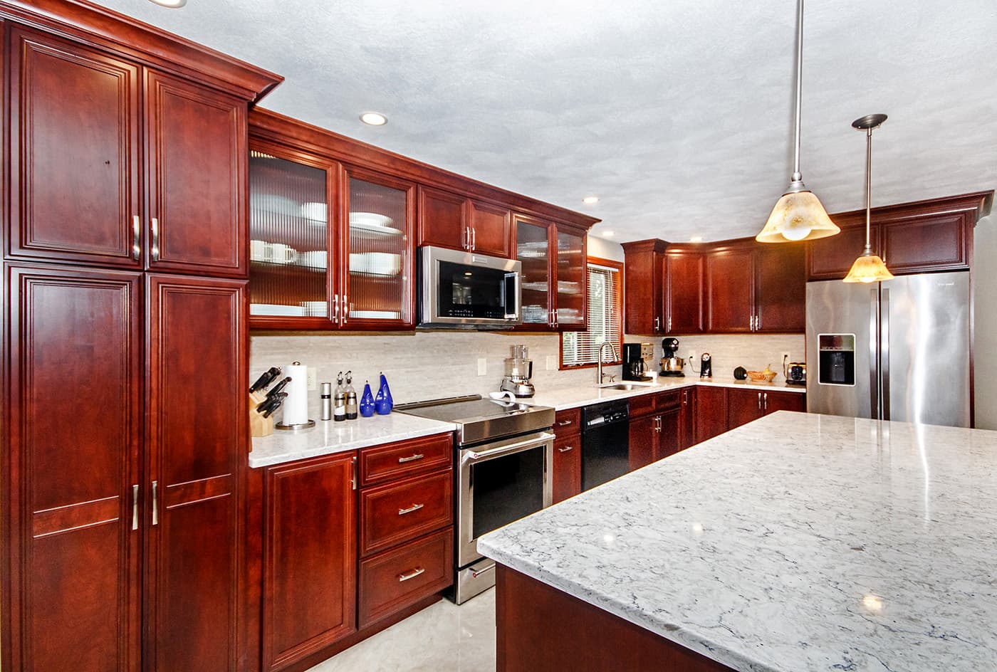 Rosenna Park Dr. Waltham kitchen with cherry cabinets, white marble-look quartz counters, and stainless appliances