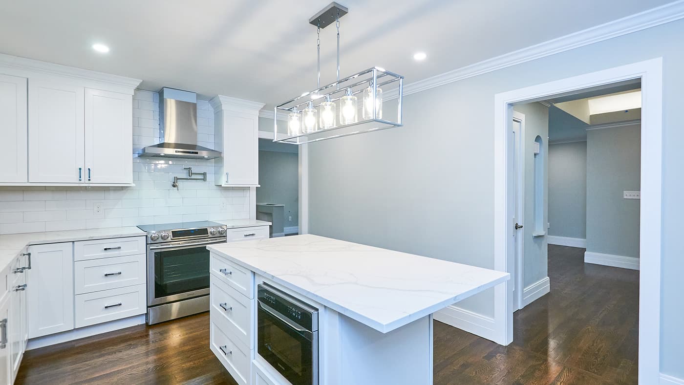 Walnut St. Newton kitchen with white cabinets, subway tile backsplash, and quartz waterfall island countertop