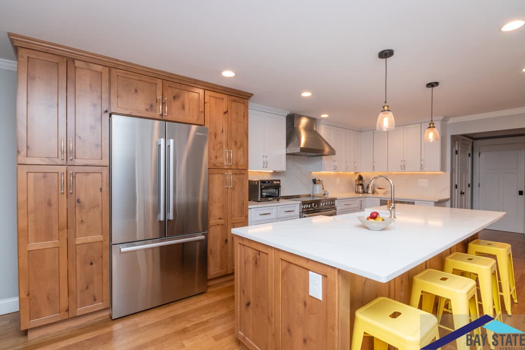 Maple Pl. Jamaica Plain kitchen with knotty wood cabinets, white quartz island, and yellow bar stools