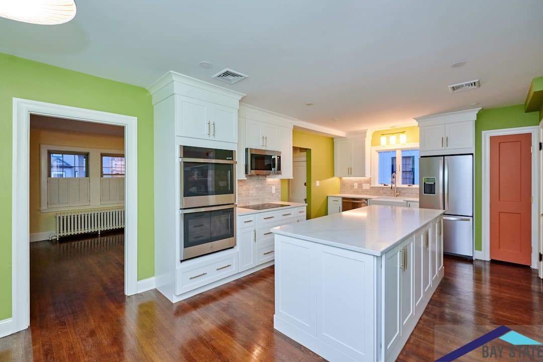 Dent St. West Roxbury kitchen with white cabinets, stacked wall ovens, and a white quartz island