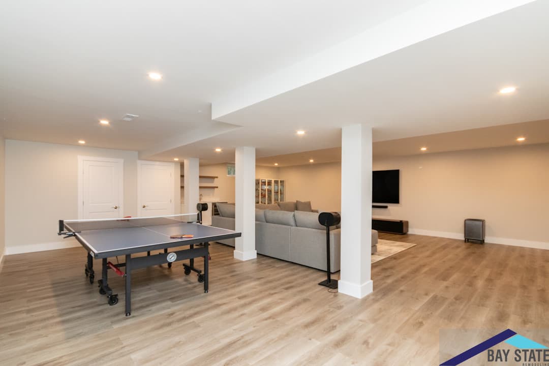 East St. Lexington finished basement after renovation, with a gray sectional sofa and floating shelves